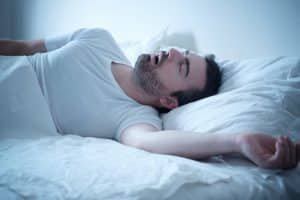 man sleeping snoring in bed