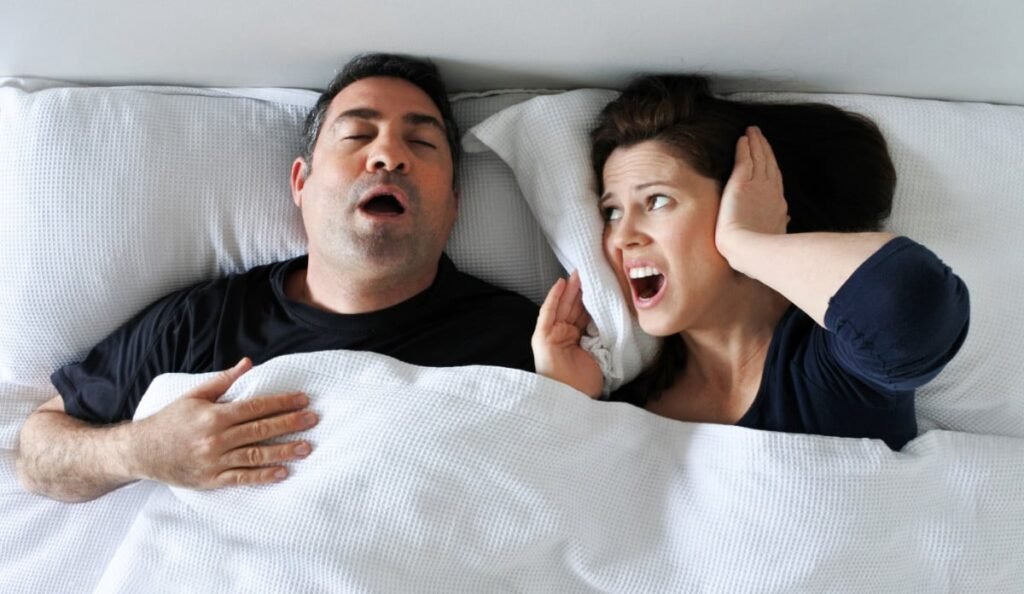 man snoring partner upset with pillow over head