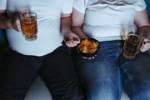 overweight couple eating in front of tv