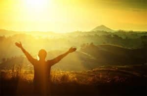 man with arms outstreatched day break